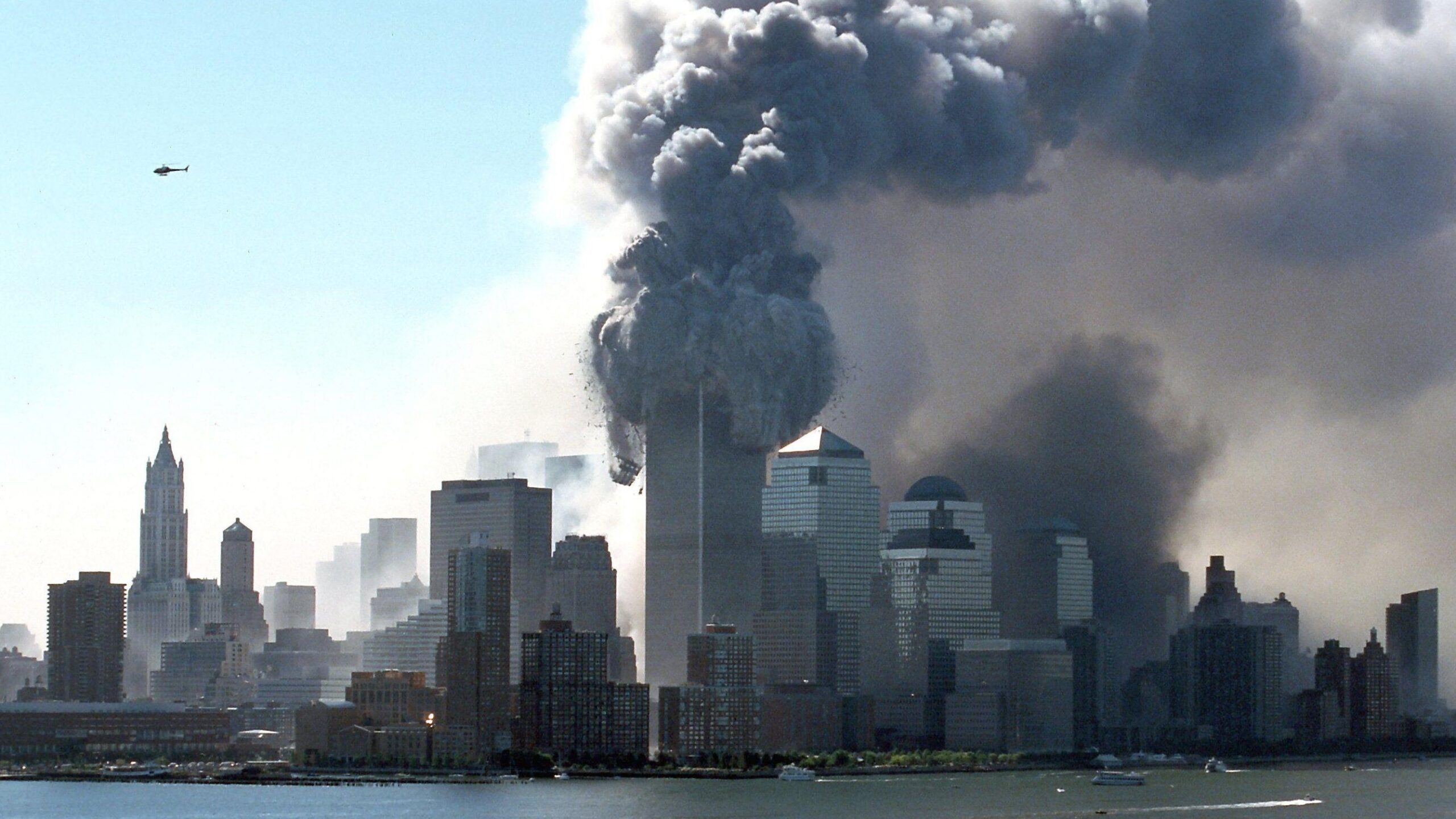 Thick black smoke emerges from the burning towers of the World Trade Center in the New York borough of Manhattan on the morning of 9/11/2001. Wreckage and building parts of the 411 meter high twin towers fly onto the street. Shortly before, two aircraft h